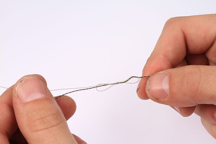 Maak de knoop vochtig met wat speeksel en trek hem al voorzichtig aan, maar nog niet helemaal strak.