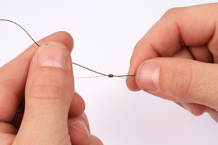 Pak nu de gevlochten lijn en maak hiermee dezelfde knoop om de hoofdlijn. Trek deze vervolgens ook aan.
